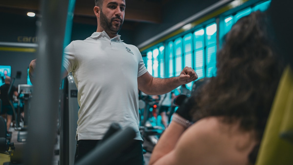 Sesión de entrenamiento en el gimnasio con un entrenador personal, enfocada en el rendimiento y el bienestar físico.